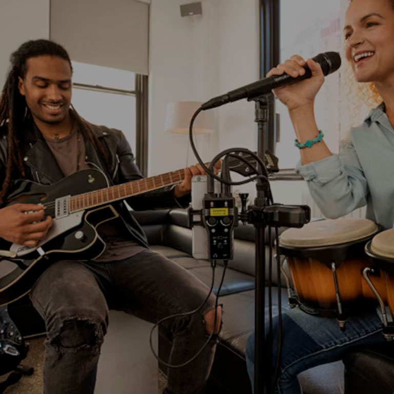 Homem e mulher sentados em uma sala tocando instrumentos e cantando utilizando a Interface de Áudio Portátil SMARTRIG Saramonic.