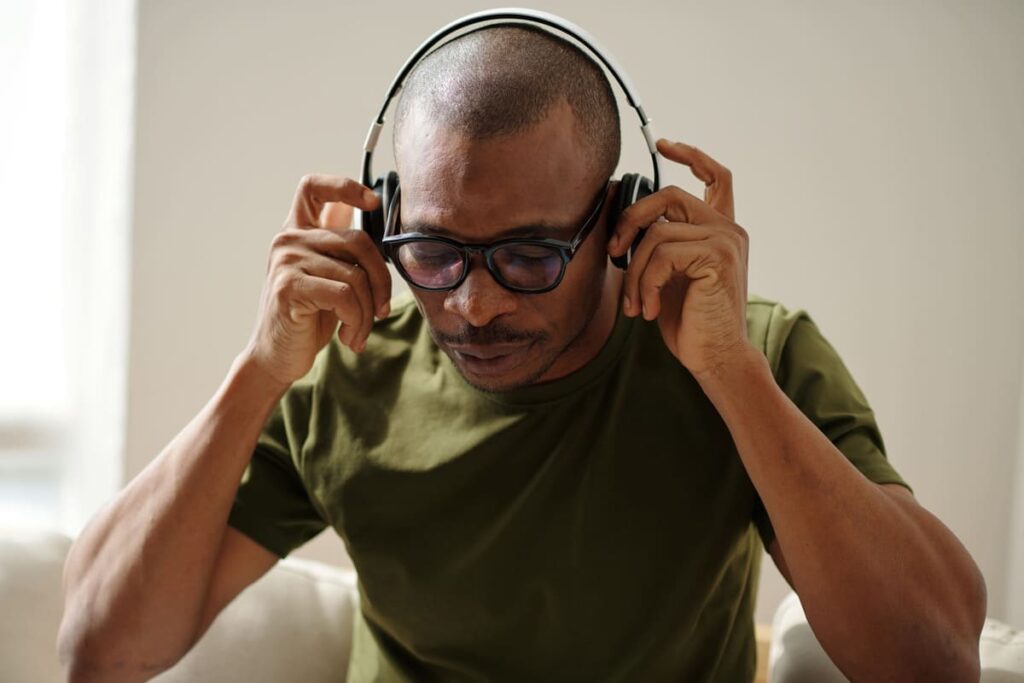 Homem afrodescendente de olhos fechados colocando fones de ouvido