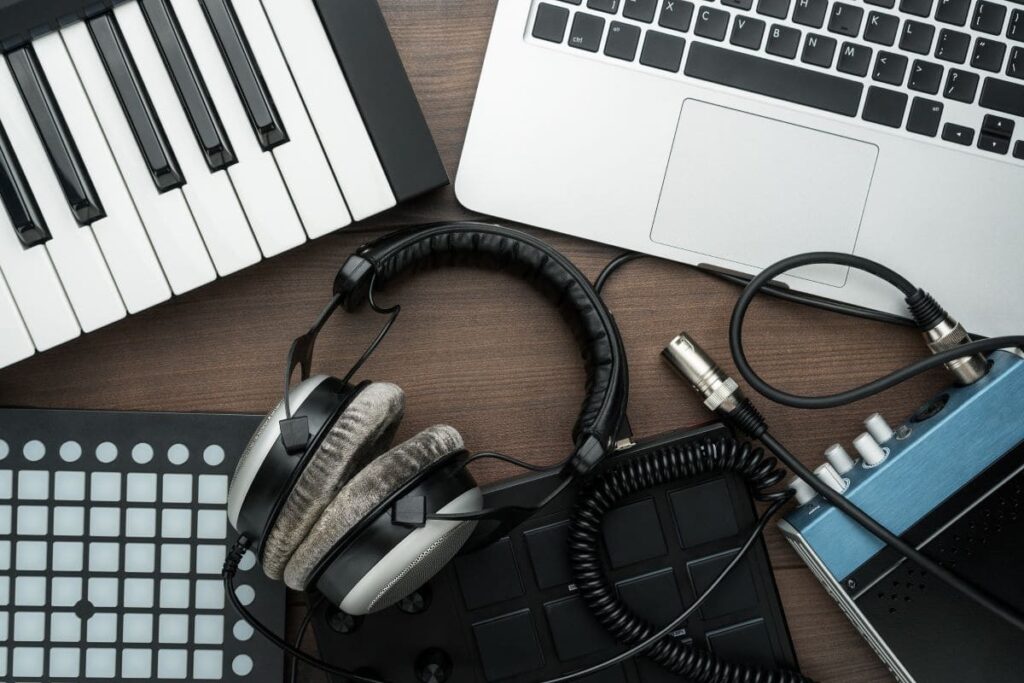 Foto tirada de cima de equipamentos de produção musical apoiados em uma mesa.