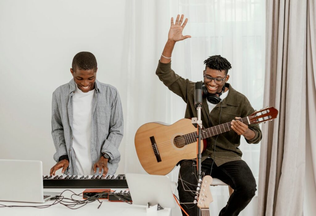 Vista frontal de músicos masculinos em casa tocando teclado elétrico e guitarra