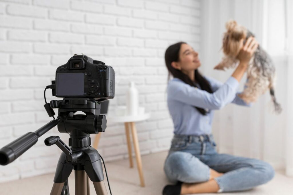 Vlogger mulher gravando enquanto levanta um cachorro em casa, em frente a uma câmera