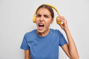 Mulher com expressão de insatisfação, puxando um lado do fone de ouvido que está em sua cabeça.